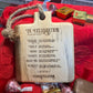 Close-up of a rustic mini cutting board with jute rope, engraved with a housewarming blessing celebrating bread, salt, wine, honey, olive oil, and a candle for prosperity and joy.