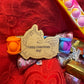 Colorful Pop It fidget toy with a laser-engraved wooden unicorn tag reading 'Happy Valentines Day!' displayed on a red textured background with chocolate candies