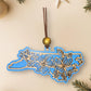 Sky Blue North Carolina dogwood ornament on a cream background with holiday decorations