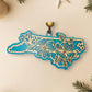 Teal North Carolina dogwood ornament on a cream background with holiday decorations