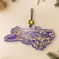 Purple North Carolina dogwood ornament on a cream background with holiday decorations