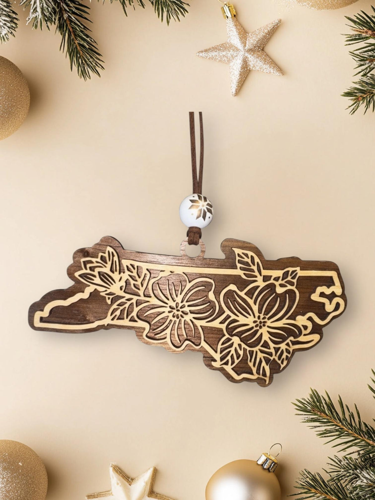 Walnut North Carolina dogwood ornament on a cream background with holiday decorations